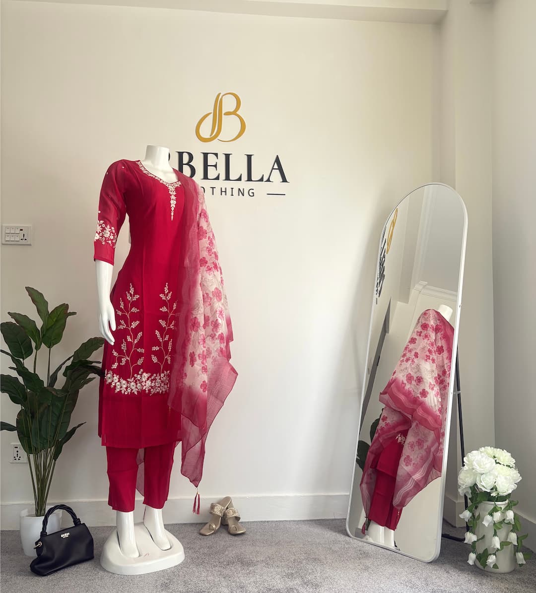 Woman wearing an elegant embroidered kurti from D Bella during the grand opening special offers banner.